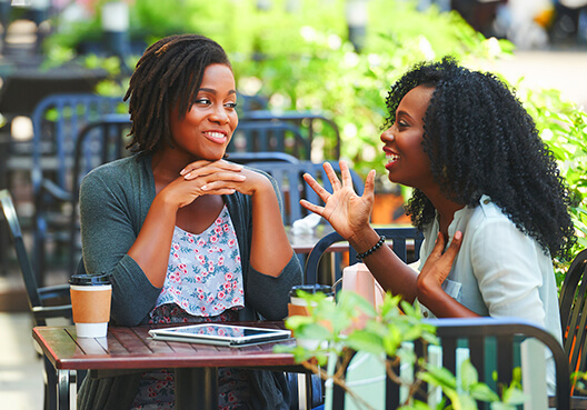 Two woman enjoy a coffee together and chat about their different financial goals. 